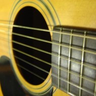 close up photo of acoustic guitar with fingerboard sound hole strings and pick guard