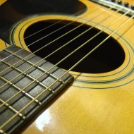 photo of an acoustic guitar sound hole with strings and pick guard