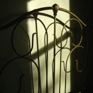 photo of antique bed headboard with shadows in sunbeam