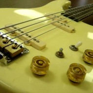 photo of electric bass guitar with strings and knobs