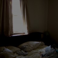 photo of messy bed with sunlight streaming through window