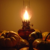 Oil Lamp with Harvest Gourds photo of burning oil lamp surrounded by various fall squash and gourds