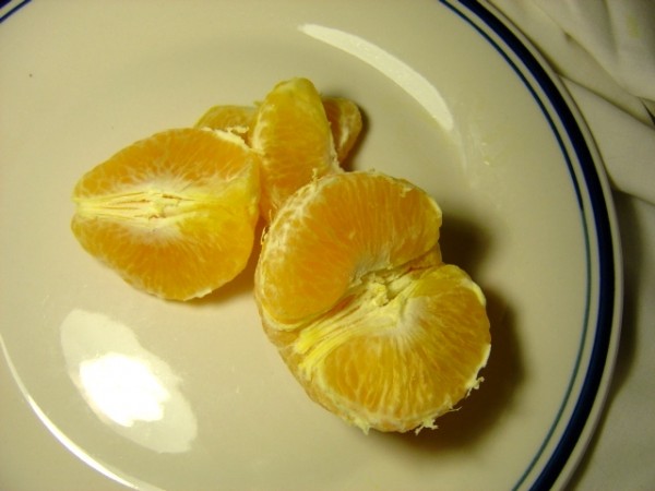 Photo of peeled orange and orange sections on a plate