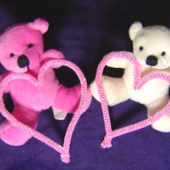 photo of two teddy bears, one pink the other white, both holding hearts