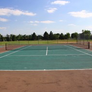 tennis court at the park Free photo of a tennis court with grass, trees and blue sky in the background