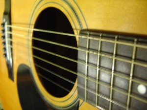 close up photo of acoustic guitar with fingerboard sound hole strings and pick guard