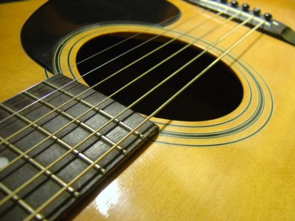 photo of an acoustic guitar sound hole with strings and pick guard