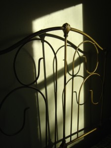 photo of antique bed headboard with shadows in sunbeam