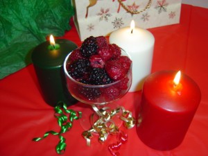 photo of dish of raspberries and blackberries with Christmas holiday candles and ribbons
