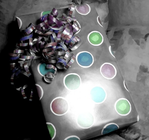black and white colorized photo of a wrapped birthday present with curly ribbon 