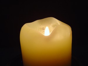 photo of cream colored candle with burning lit flame in dark