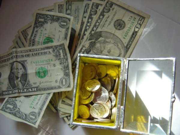 photo of a variety of dollar bills with a glass box full of coins