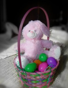 colorized photo of stuffed bunny in an easter basket with colorful eggs