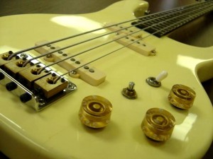 photo of electric bass guitar with strings and knobs