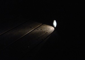 photo of flashlight shining on deck boards in darkness of night