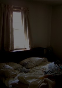 photo of messy bed with sunlight streaming through window