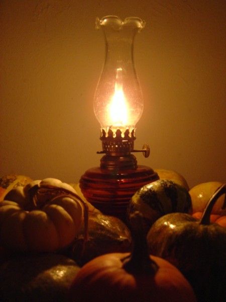 Oil Lamp with Harvest Gourds photo of burning oil lamp surrounded by various fall squash and gourds