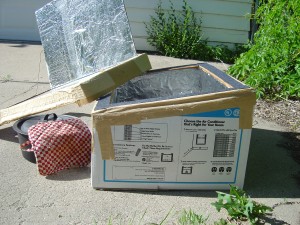 photo of home made solar box cooker with pot of food next to it