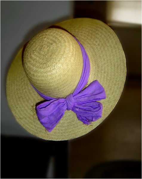 Photo of straw hat hanging on edge of a chair