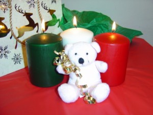 Photo of white teddy bear with burning Christmas candles