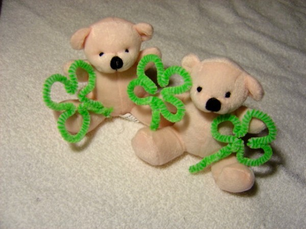 Photo of Two white teddy bears holding shamrocks