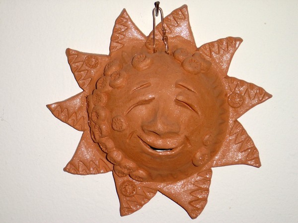 Photo of a terra cotta ornament of a smiling sun