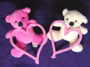 photo of two teddy bears, one pink the other white, both holding hearts