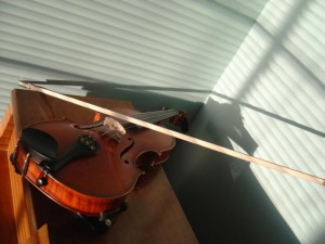 Photo of a violin with shadows from the window blinds