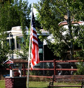 Free photograph of an American Flag on a flagpole next to a garden well and bench
