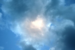 This free photo features the sun shining through clouds in a blue sky