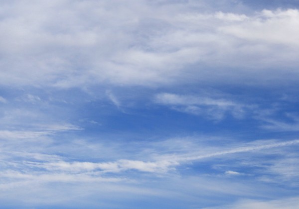 Free photograph of a blue sky with white clouds and a visible airplane trail