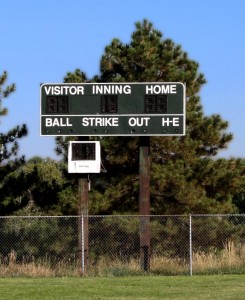 Free photo of a baseball scoreboard with pine trees in the background