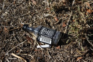 free photo of a Jack Daniels bottle tossed on the ground with cigarette butt